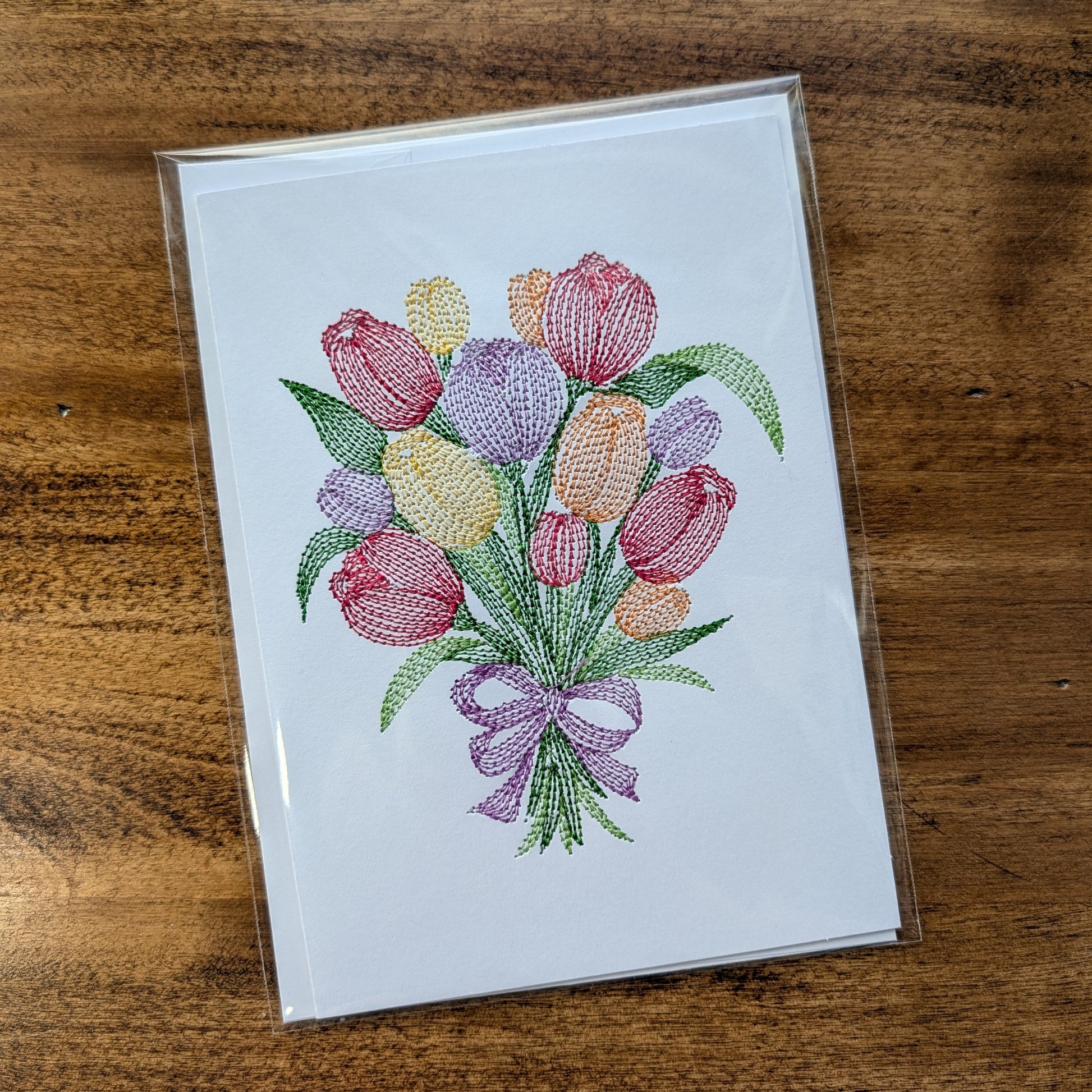 Card with embroidered tulip design on a wooden surface