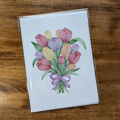 Card with embroidered tulip design on a wooden surface