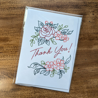 Card with floral designs and 'Thank You' text on a wooden surface